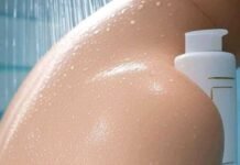 The Secret to Glowing Skin? It Might Be Your Body Wa Close-up of dewy skin with water droplets in a modern shower, featuring a sleek glowing skin body wash bottle in soft blues and whites.