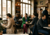 Quiet Luxury Is Fading—What Stylish Americans Want Now Woman in green jacket sitting in busy traditional French bistro.
